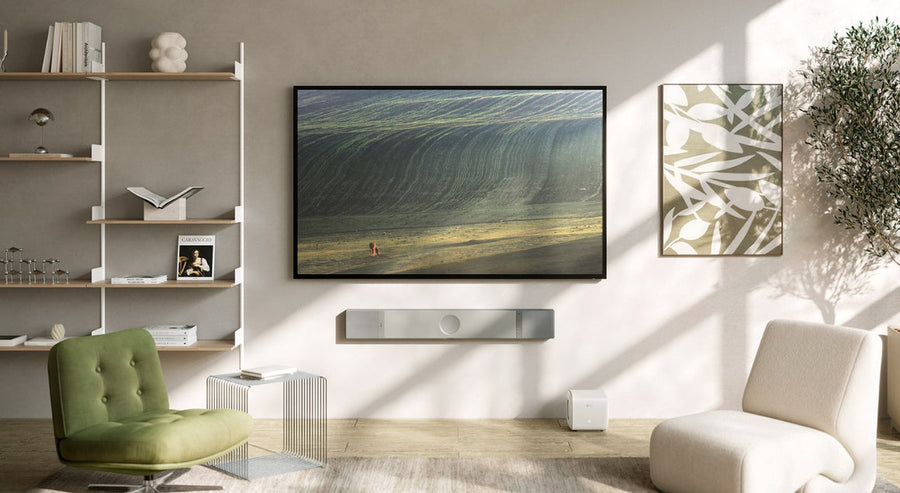 Modernes Wohnzimmer mit wandmontiertem Fernseher und eleganter KEF-Soundbar, die ein hochwertiges Heimkino-Setup im natürlichen Licht zeigt.