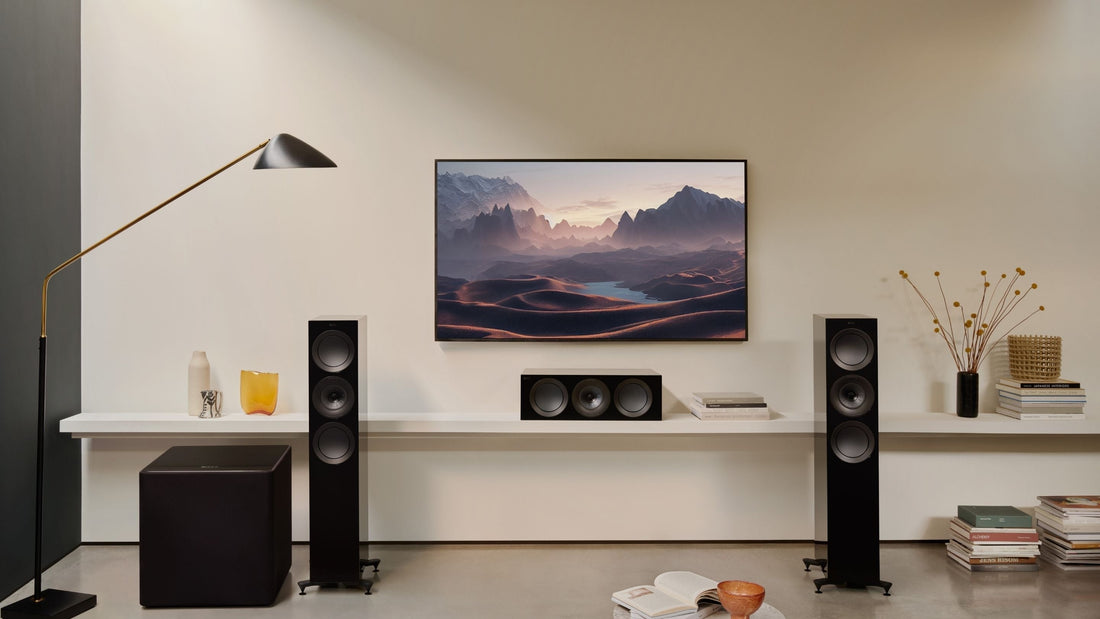 A modern living room with contemporary furniture, TV, KEF Kube 12 MIE, and R5 Meta HiFi speaker, illuminated by natural light.