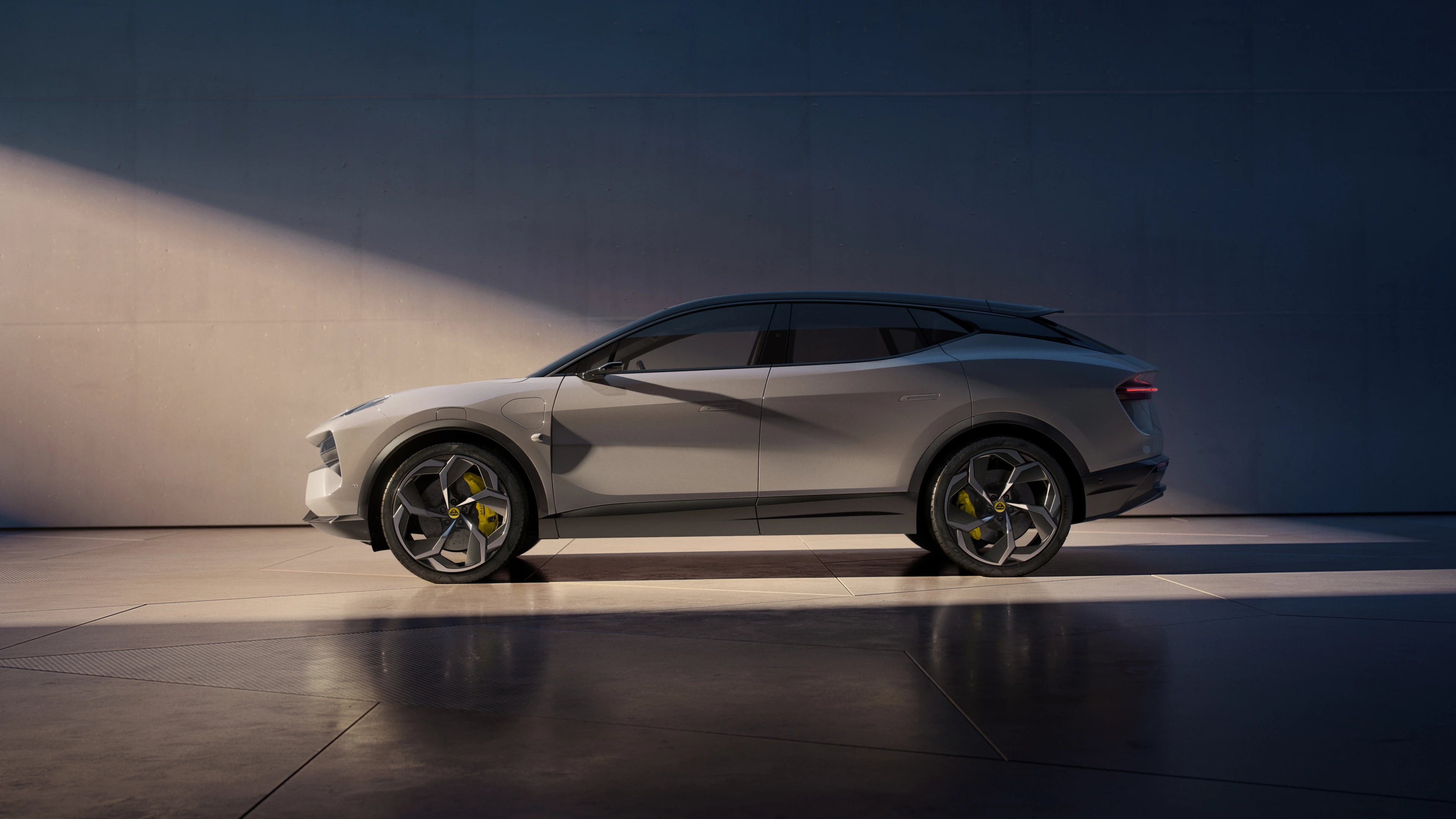 A Lotus Eletre shown in side profile against a dark studio backdrop with dramatic lighting and floor reflections.